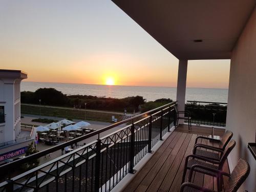 a balcony with a view of the ocean at sunset at Aparthotel Waterkant Suites - Fewos am Meer mit SPA in Börgerende-Rethwisch