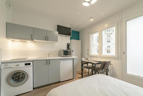 - une cuisine blanche avec un lave-linge et une table dans l'établissement apparthotel-gare-chambery, à Chambéry