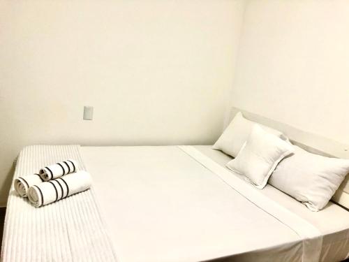 a white bed with two rolled towels on it at Casa das Flores in Florianópolis