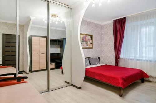 1 dormitorio con cama roja y espejo en Good Home en Sumy
