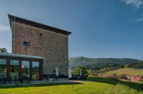 a large brick building with tables and chairs in a field at Hotel Torre Zumeltzegi in Oñate
