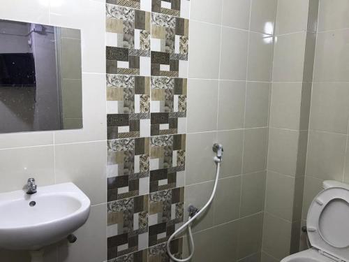 a bathroom with a sink and a toilet and a mirror at Axlite Hotel in Taiping