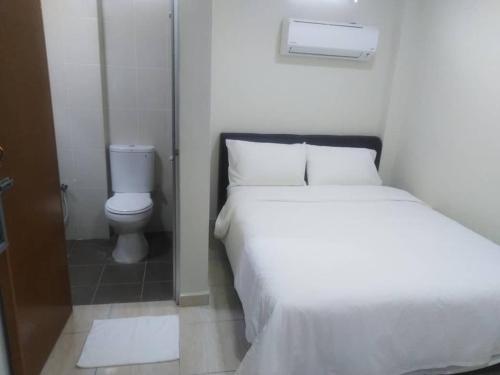 um quarto com uma cama branca e um WC em Axlite Hotel em Taiping