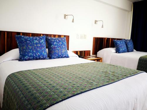 two beds in a hotel room with blue pillows at Hotel Rosita in Puerto Vallarta
