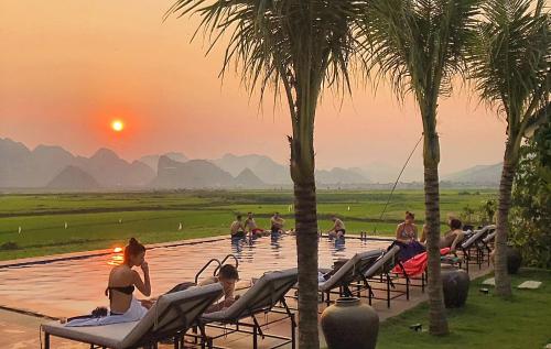 a group of people sitting in the infinity pool at sunset at Karst Villas Phong Nha in Phong Nha