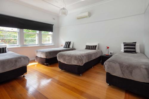 three beds in a room with wood floors at 2easy on Hargreaves in Bendigo