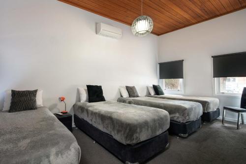 a bedroom with two beds and a table with a lamp at 2easy on Hargreaves in Bendigo