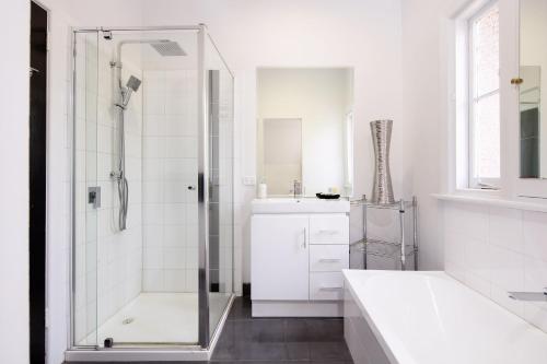 a white bathroom with a shower and a sink at 2easy on Hargreaves in Bendigo