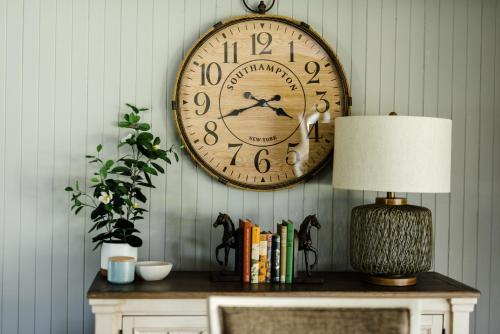 eine große Uhr an der Wand über einem Tisch mit einer Lampe in der Unterkunft Walnut Tree Cottages in Whorouly