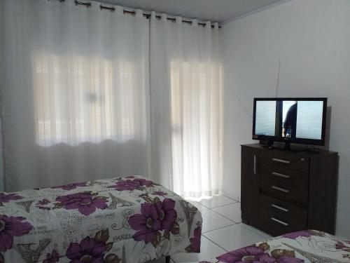 a bedroom with a television on a dresser with a bed at Hospedagem Clima do Lago in Cunha