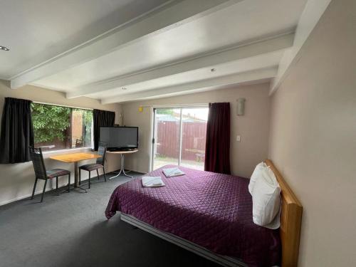 una camera con letto, scrivania e finestra di Blenheim Road Motor Lodge a Christchurch
