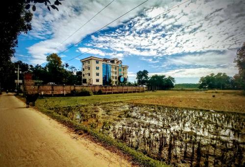 a building on the side of a dirt road next to a field at Grand Selim Resort & Tour – GSRT in Sreemangal