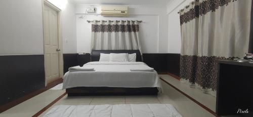 a bedroom with a bed with white sheets and a window at Sai Pavilion in Puttaparthi