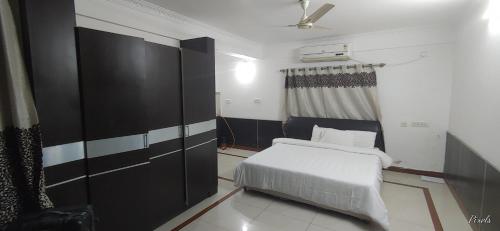 a bedroom with a white bed and a black cabinet at Sai Pavilion in Puttaparthi