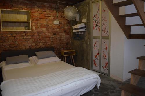 a bedroom with a bed and a brick wall at Dou Houz Georgetown in George Town