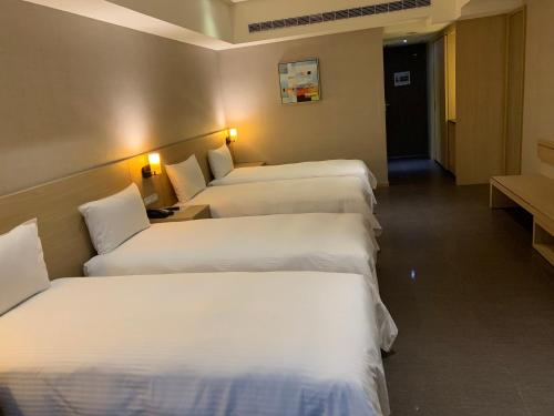 a row of four beds in a hotel room at Grand Bay Resort Hotel in Hengchun