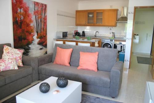 a living room with a couch and a kitchen at Apartamento luminoso Urb. Quinta das Palmeiras in Porches