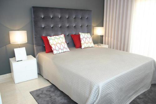 1 dormitorio con 1 cama grande con almohadas rojas en Apartamento luminoso Urb. Quinta das Palmeiras en Porches