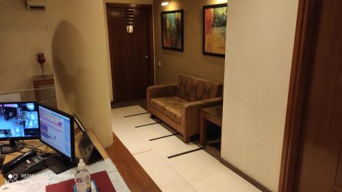 a living room with a couch and a computer on a desk at Hotel Broadway in Chandīgarh
