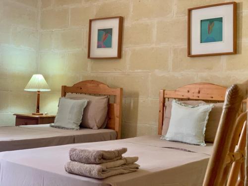 a room with two beds with towels on a table at Tal-Mirakli in Għarb
