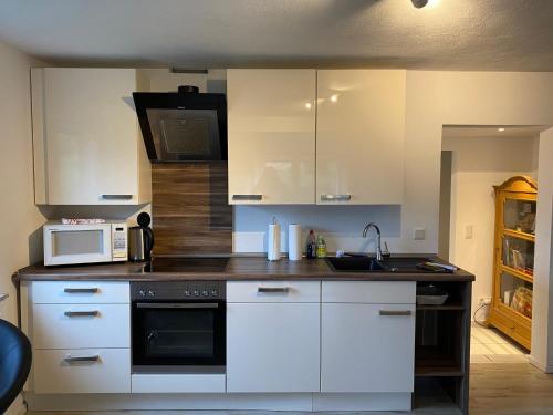 a kitchen with white cabinets and a microwave at über den Dächern von Neheim I in Arnsberg