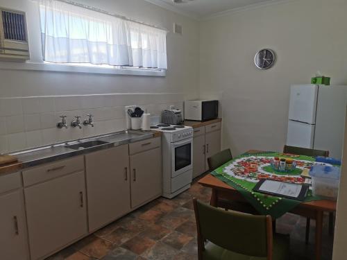 uma cozinha com uma mesa, um fogão e um frigorífico em Kimba Units em Kimba