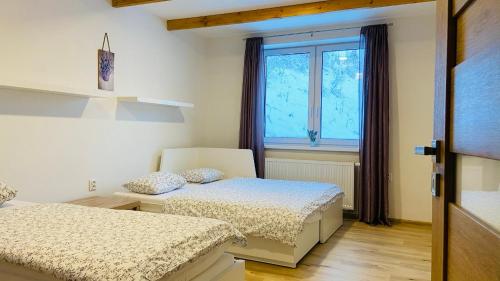 a bedroom with two beds and a window at Chalupa u Bohumila in Rybná nad Zdobnicí