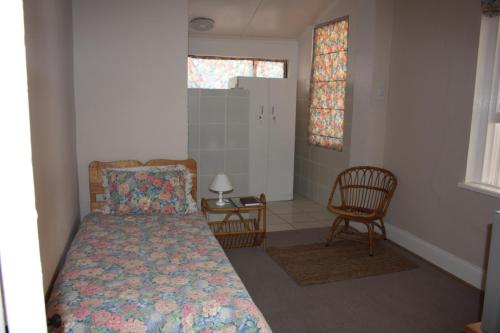 a small bedroom with a bed and a chair at Karoopark Guest House in Graaff-Reinet