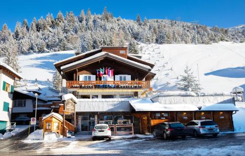 a ski lodge with cars parked in the snow at Hotel TURNA Malbun in Malbun