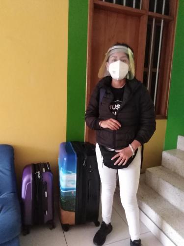 a woman wearing a mask standing next to luggage at Hospedaje de Lidia in Lima