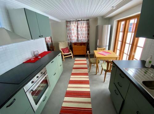 a kitchen with green cabinets and a dining room with a table at Franshammars vandrarhem in Hassela