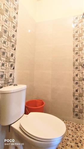a bathroom with a white toilet and a bucket at Monte Villa Guest House in Candolim