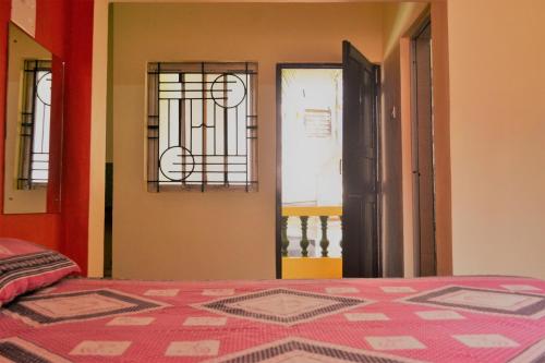 a bedroom with a bed and two windows and a door at Monte Villa Guest House in Candolim