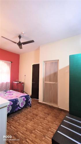 an empty room with a bed and a ceiling fan at Monte Villa Guest House in Candolim