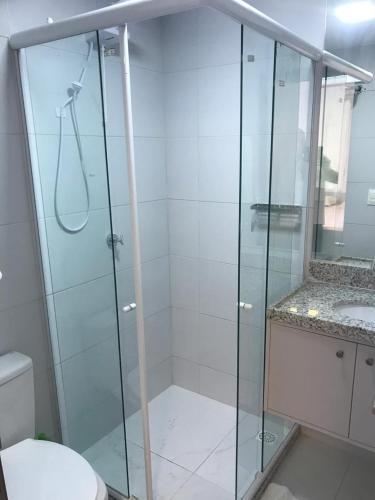 a bathroom with a glass shower with a sink at VUARNET FLATS in João Pessoa