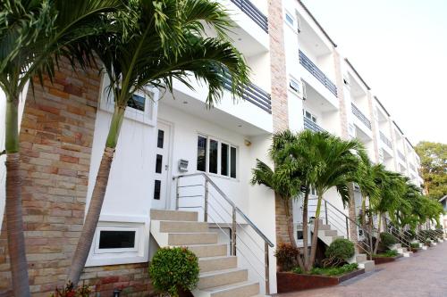 un bâtiment blanc avec des palmiers devant lui dans l'établissement Hidden Palm Pool Villas, à Pattaya (nord)