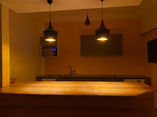 une cuisine avec deux lampes suspendues et une table en bois dans l'établissement Gîte Le Toubé, à Saint-Louis