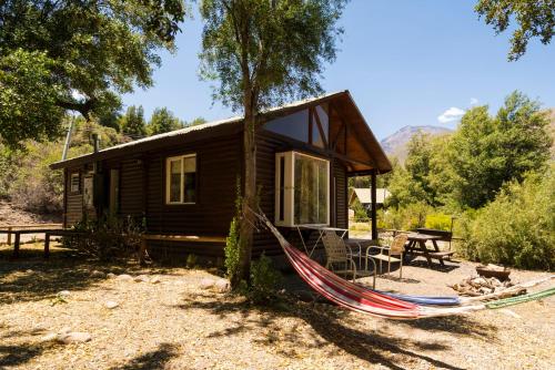 une cabane en rondins avec un hamac en face de celle-ci dans l'établissement Cabañas Emporio de la Meme, à San José de Maipo