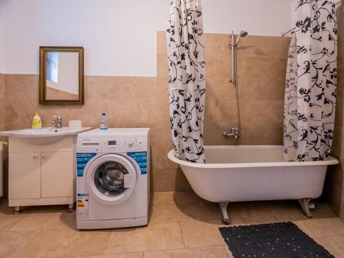 a bathroom with a tub and a washing machine at Fresh Air Apartment in Braşov