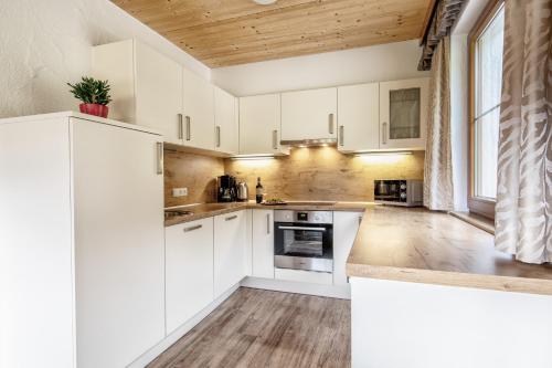 a kitchen with white cabinets and a wooden ceiling at Chalets Hotter - Ferienhaus mit E-Ladestation in Zell am Ziller