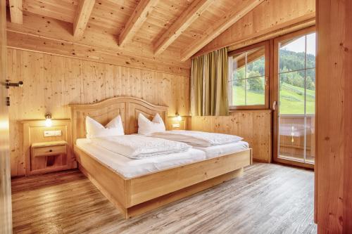 a bedroom with a bed and a large window at Chalets Hotter Ferienhaus mit E-Ladestation in Zell am Ziller