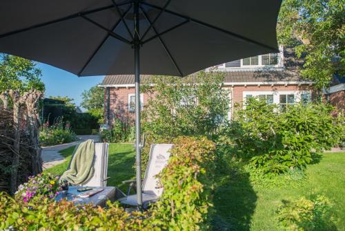 an umbrella and chairs in the yard of a house at Broeks' Bed En Brood in Meerkerk