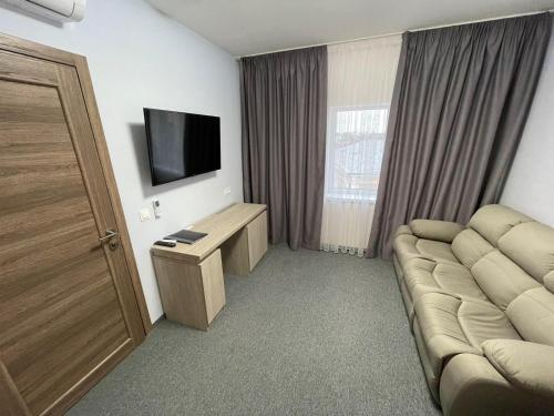 Hotelzimmer mit Sofa und TV in der Unterkunft Park Hotel in Nizhyn