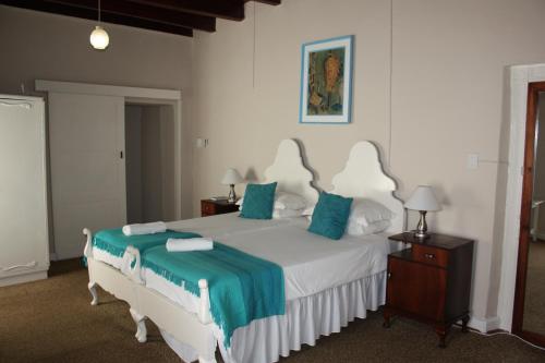 a bedroom with a large white bed with blue pillows at Karoopark Guest House in Graaff-Reinet