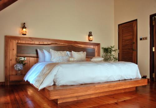 a bedroom with a large bed with a wooden headboard at Cottage San Francesco in Nuwara Eliya