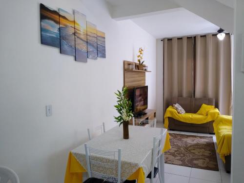 ein Wohnzimmer mit einem Tisch und einem gelben Sofa in der Unterkunft Condomínio Villagio II in Caraguatatuba