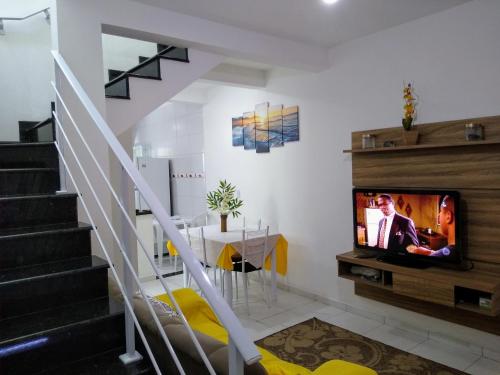 ein Wohnzimmer mit einem TV und einer Treppe in der Unterkunft Condomínio Villagio II in Caraguatatuba