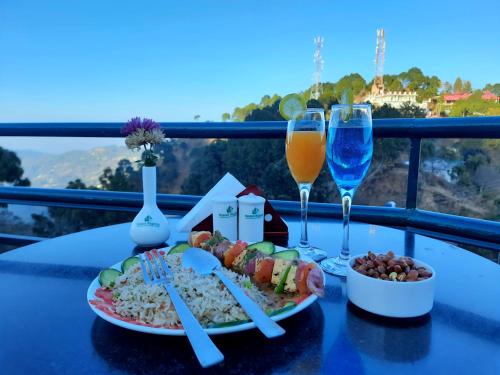a table with two plates of food and glasses of wine at Hotel Kasauli Regency Stags Not Allowed in Kasauli