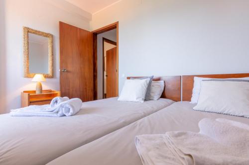 フンシャルにあるCondo Magnoliaのベッドルーム1室(白いシーツと鏡付きのベッド2台付)