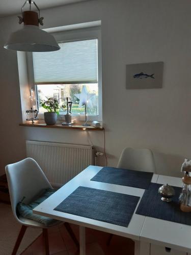 a dining room table with chairs and a window at Ferienhaus Elisenhuus in Tönning